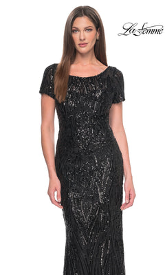 A woman wearing a black, short-sleeved, floor-length La Femme 31852 gown covered in vertical sequin patterns.