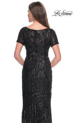 Back view of a woman wearing a black short-sleeved, floor-length La Femme 31852 sequin formal dress with vertical patterns.