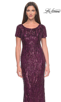 A woman wears a floor-length, short-sleeved plum Long Formal Dress: La Femme 31852 covered in intricate, dark sequined patterns.