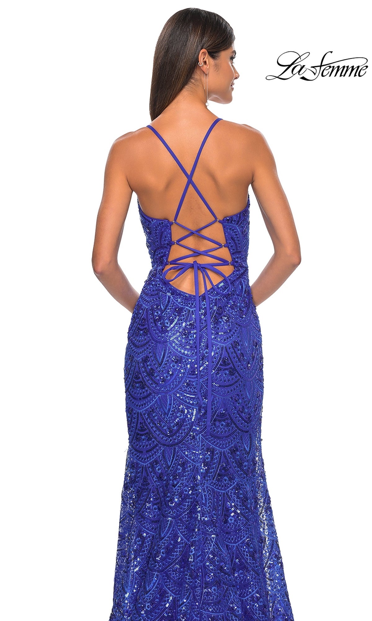 A woman stands facing away in the La Femme Sequin-Print Long Prom Dress 31865, a royal blue gown with sparkling sequins and a crisscross lace-up open back. La Femme logo appears in the top right corner.