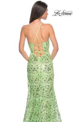A woman wearing the La Femme Sequin-Print Long Prom Dress 31865, featuring green sequins and lace-up crisscross back straps, stands with her back to the camera. The La Femme logo appears in the top right corner.
