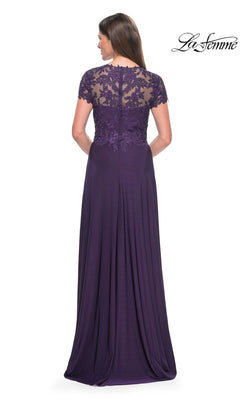 A woman faces away from the camera in the La Femme Cap Sleeve Long Purple Prom Dress 31906, featuring eggplant lace detailing on the upper back and sleeves, a zipper closure, and a flowing A-line skirt.
