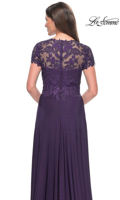 A woman shown from behind wears the La Femme Cap Sleeve Long Purple Prom Dress 31906, featuring an a-line silhouette, lace detailing on the upper back, and short sleeves.