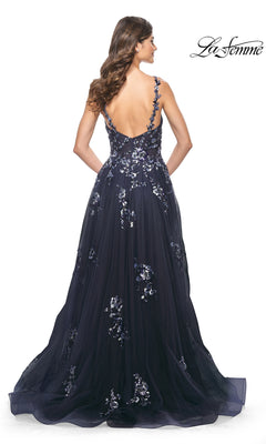 A woman stands with her back to the camera wearing the La Femme Navy Long Sequin-Print Prom Dress 31936, featuring floral embroidery and an open back.