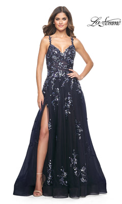 A woman stands against a white background wearing the La Femme Navy Long Sequin-Print Prom Dress 31936, a floor-length gown with spaghetti straps, a sweetheart neckline, and a thigh-high slit.