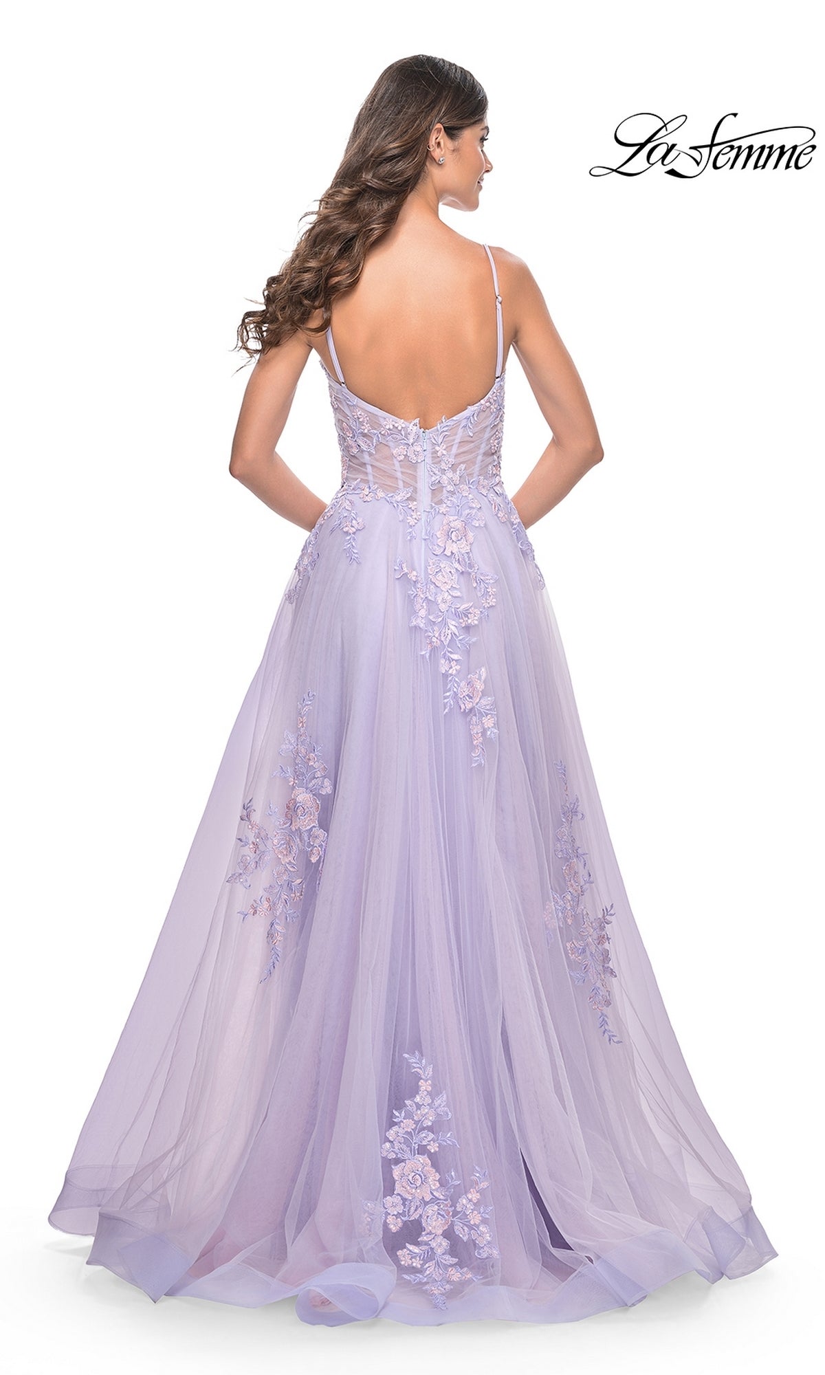 A woman wearing the La Femme Embroidered-Lace Long Prom Dress 31939, a lavender floor-length gown with thin straps and a sheer back, stands facing away from the camera. The La Femme logo appears in the top right corner.
