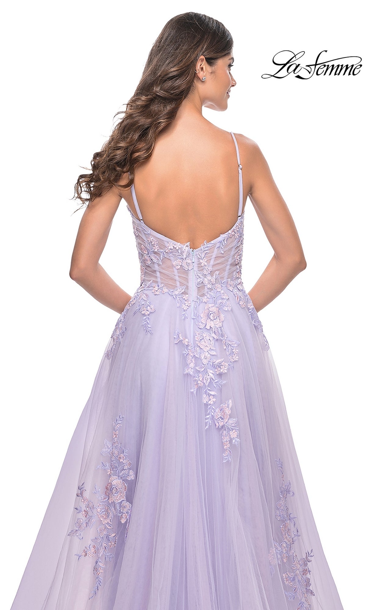 A woman is shown from the back wearing the La Femme Embroidered-Lace Long Prom Dress 31939, featuring lavender tulle, floral embroidery, spaghetti straps, a fitted bodice, and an elegant flowing skirt.