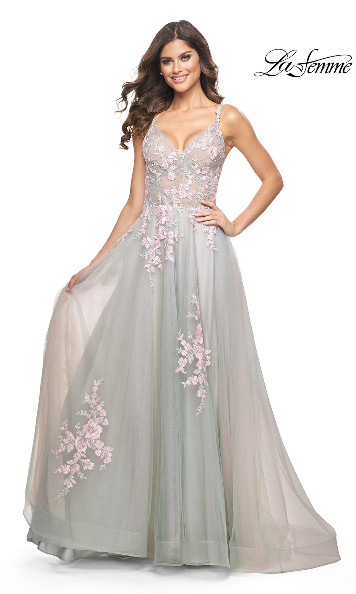 A woman wears the La Femme Embroidered-Lace Long Prom Dress 31939 in pastel green, featuring pink floral embroidery and elegant lace details, while standing and holding the skirt. The La Femme logo is in the top right corner.