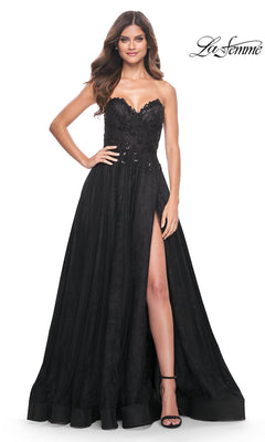 A woman stands against a white background wearing the La Femme Strapless Long Prom Ball Gown 31954, featuring a sweetheart neckline, black evening silhouette, floral embellishments, and a high slit.