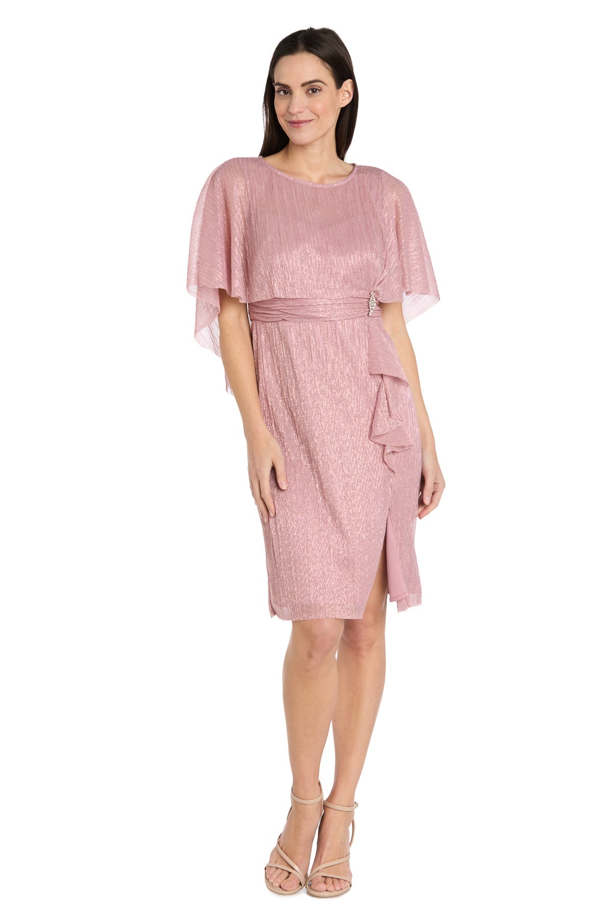 A woman wears the Caped Knee-Length Party Dress: R&M Richards 3195P in shimmery pink, featuring short flutter sleeves, a belted waist, and beige strappy heels.