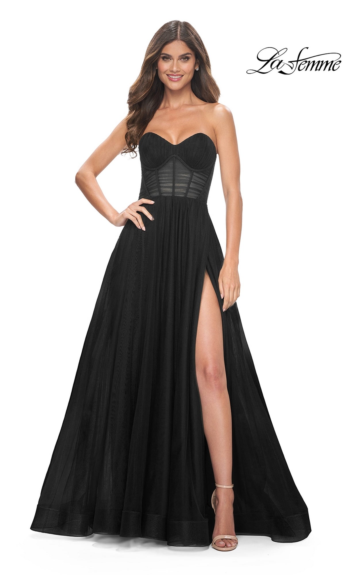 A woman stands with one hand on her hip, wearing the La Femme Strapless Long A-Line Prom Dress 31971 featuring a mesh corset bodice and high side slit.