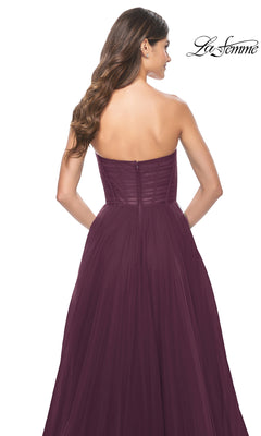 A woman with long brown hair elegantly models the La Femme Strapless Long A-Line Prom Dress 31971 in burgundy, featuring a fitted bodice and floor-length skirt, seen from the back.