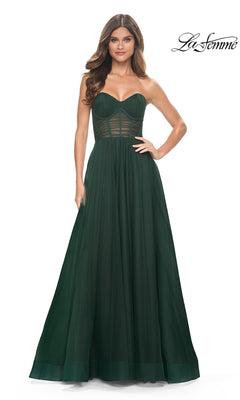A woman models the La Femme Strapless Long A-Line Prom Dress 31971 in dark green, with a structured bodice and sheer panel details, against a plain white background.