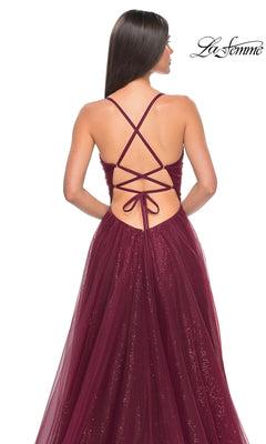 A woman wears the La Femme Long Sequin A-Line Prom Dress 31986, featuring a burgundy glittery tulle skirt and crisscross lace-up open back. The La Femme logo appears in the top right corner.