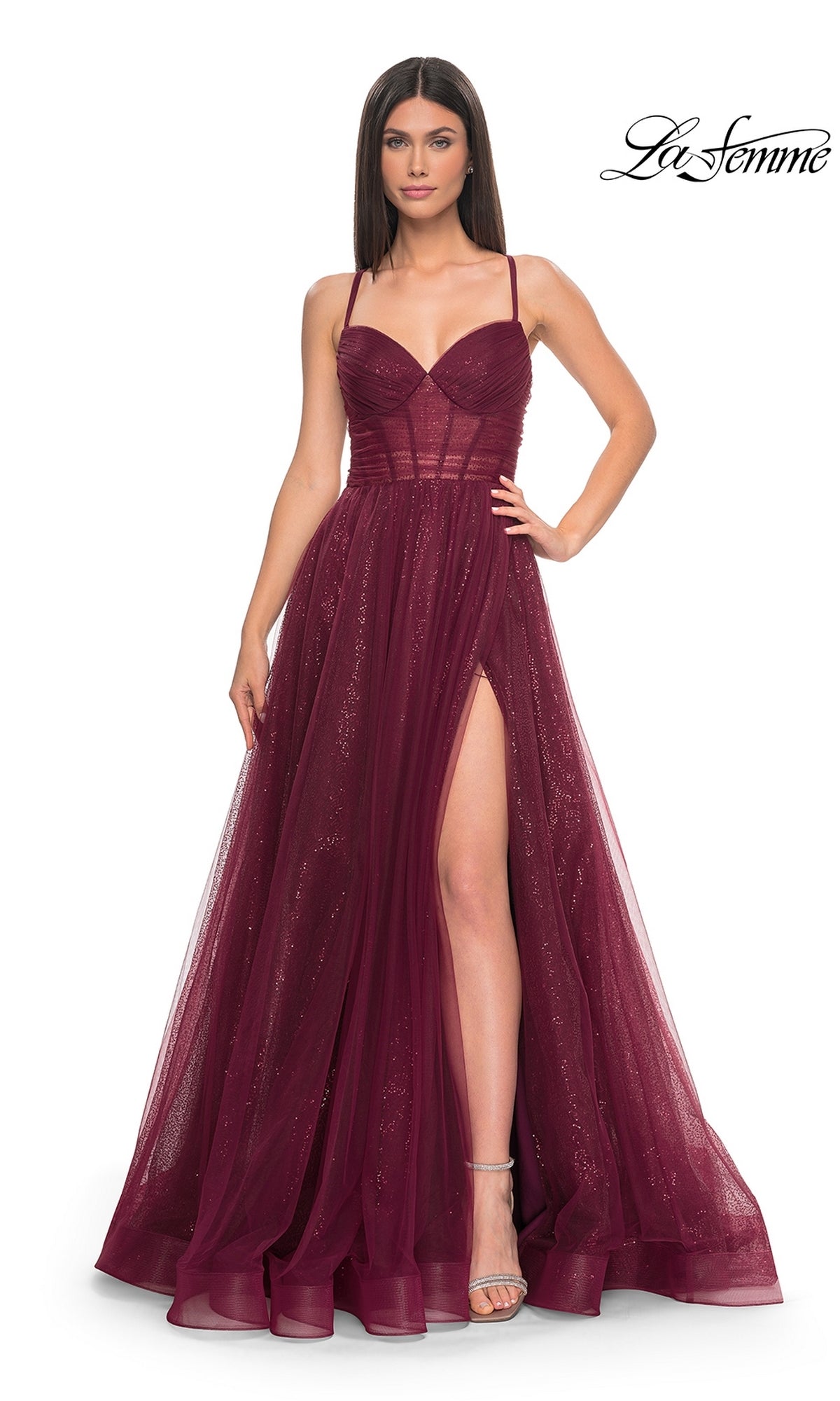 Woman wearing a dark berry La Femme Long Sequin A-Line Prom Dress 31986, featuring thin straps, a fitted bodice, and a high slit, standing against a plain white background.
