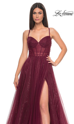 Woman in a sleeveless, deep red sequin A-line prom dress (La Femme 31986) with a sweetheart neckline, thin straps, fitted bodice, and high slit, standing against a plain background. "La Femme" logo appears in the top right corner.