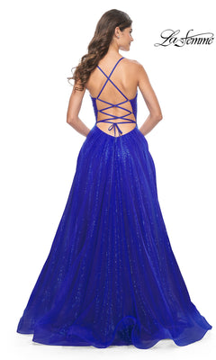 A woman is seen from behind wearing the La Femme Long Sequin A-Line Prom Dress 31986, a floor-length, sparkly royal blue gown featuring a crisscross lace-up open back.