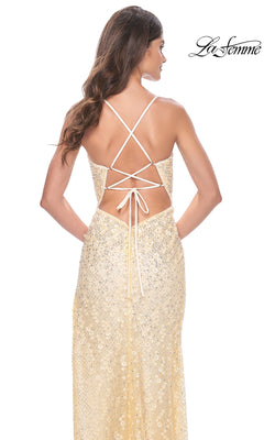 Woman wearing a sparkly, light gold Strappy-Back Long La Femme Beaded Prom Dress 31993 with a lace-up open back and thin crisscross straps, standing with her back to the camera.