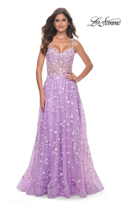 A woman models the La Femme Floral-Embellished Long Prom Dress 31996, showcasing its sheer bodice and delicate floral appliqués on an A-line silhouette against a white background. The La Femme logo is in the top right corner.