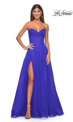 A woman smiles radiantly, posing with one hand on her hip in the La Femme Strapless Long Prom Ball Gown 31997, a royal blue dress featuring a sweetheart neckline, high slit, and subtle sparkly details.