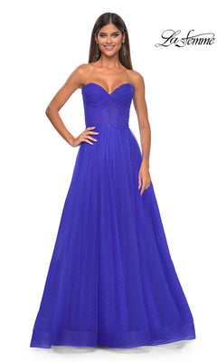 A woman in the La Femme Strapless Long Prom Ball Gown 31997, featuring a fitted bodice, subtle sparkles, and a floor-length royal blue skirt, stands against a white background.