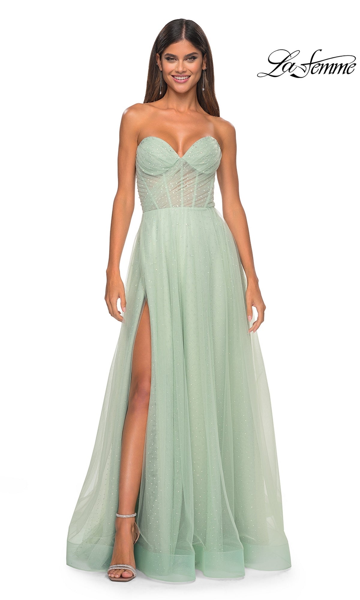A woman wears the La Femme Strapless Long Prom Ball Gown 31997 in sage, a floor-length A-line dress featuring a sweetheart neckline, fitted bodice, high slit, and sparkly tulle—perfect for prom.