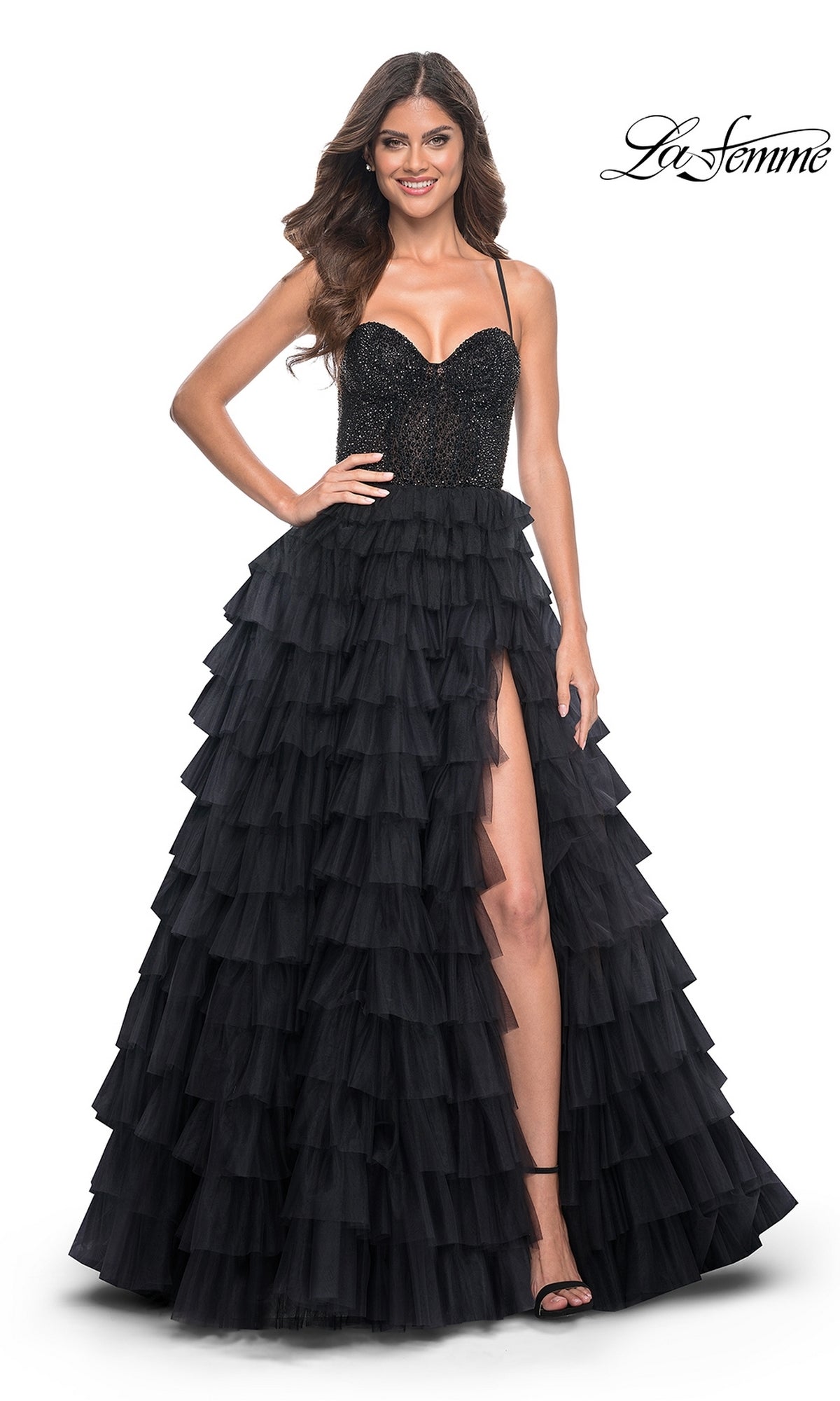 Woman wearing La Femme Long Ruffled Prom Ball Gown 32002, a sleeveless black dress with beaded bodice, spaghetti straps, and a tiered skirt featuring ruffles and a high slit; her hair is styled in loose waves.