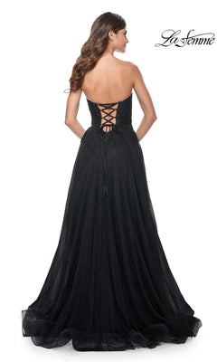 A woman models the La Femme Long Black Strapless Prom Dress 32005, featuring a lace-up back, beaded detailing, and a floor-length A-line skirt for an elegant formal look.