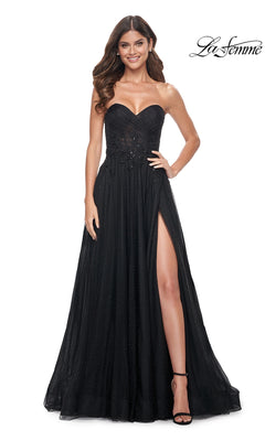 A woman in the La Femme Long Black Strapless Prom Dress 32005—with high slit—stands smiling. She has long wavy hair, black heels, and the "La Femme" logo is visible in the top right corner.