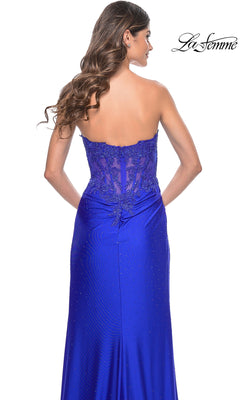 Woman in the La Femme Sheer-Waist Strapless Long Prom Dress 32011, featuring beaded detailing, a lace-up back, and a royal blue color, stands with her back to the camera.