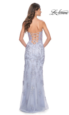 A woman stands facing away in the La Femme Sheer-Corset Long Prom Dress 32013, a light lavender strapless gown with a sweetheart neckline, lace-up back, and floral embroidery. The "La Femme" designer logo appears in the top right corner.