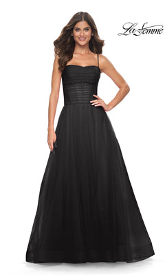 A woman stands against a white background wearing the La Femme Sheer-Waist Long Prom Ball Gown 32017, a black sleeveless dress with spaghetti straps, fitted bodice, full tulle skirt, and an elegant silhouette.