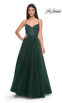 A woman stands facing forward in the La Femme Beaded Long A-Line Prom Dress 32020, a dark green gown with thin straps, fitted beaded bodice, and a sheer sparkling overlay for an elegant floor-length look.