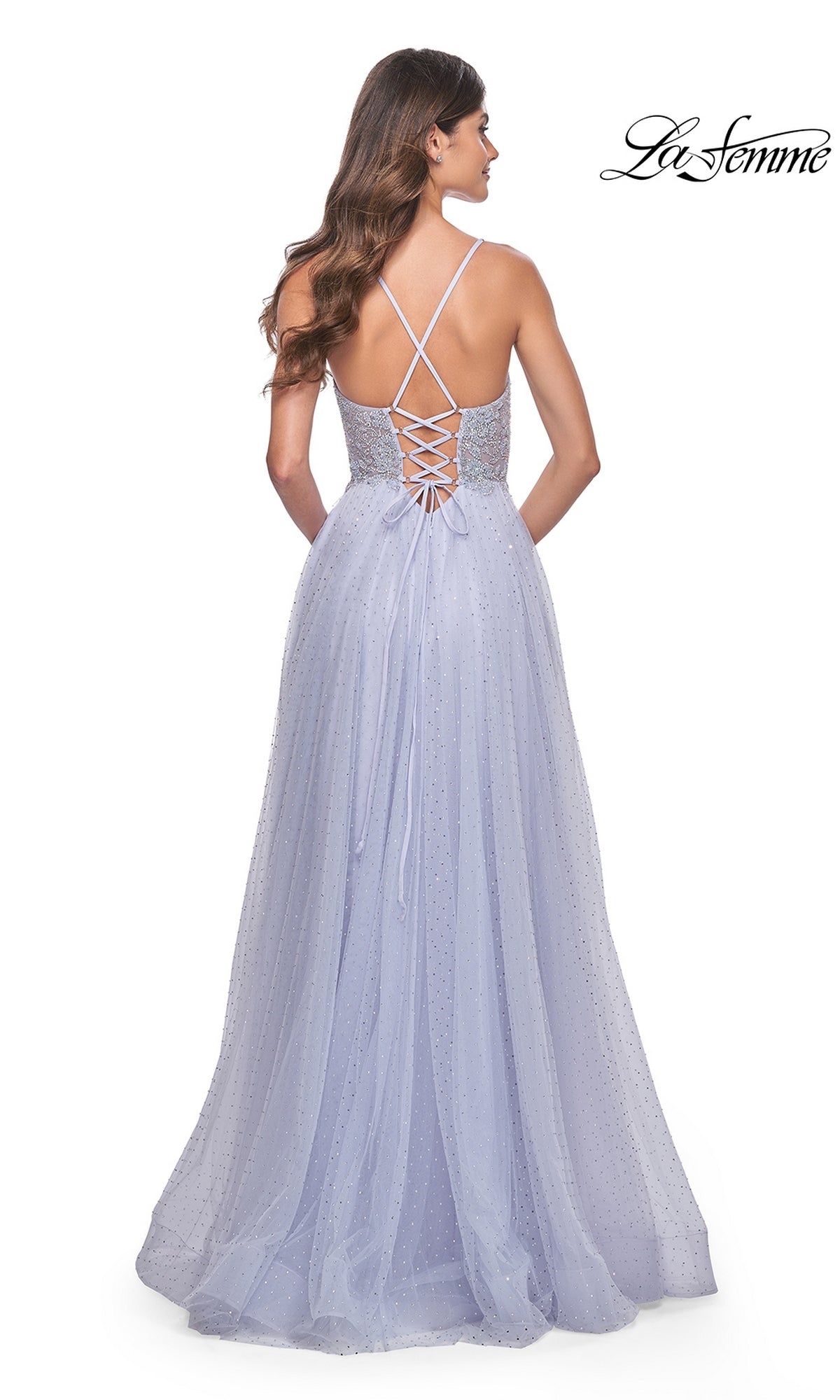 A woman is shown from behind wearing the La Femme Beaded Long A-Line Prom Dress 32020, featuring a light purple hue, long formal silhouette, thin criss-cross straps, and a lace-up back detail.