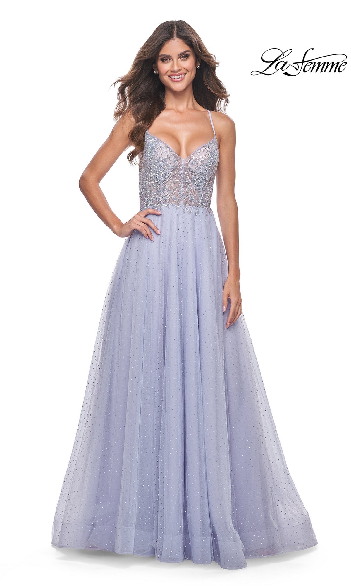 A woman smiles against a white background wearing the La Femme Beaded Long A-Line Prom Dress 32020 in light purple, featuring a fitted bodice with thin straps and a full tulle skirt.
