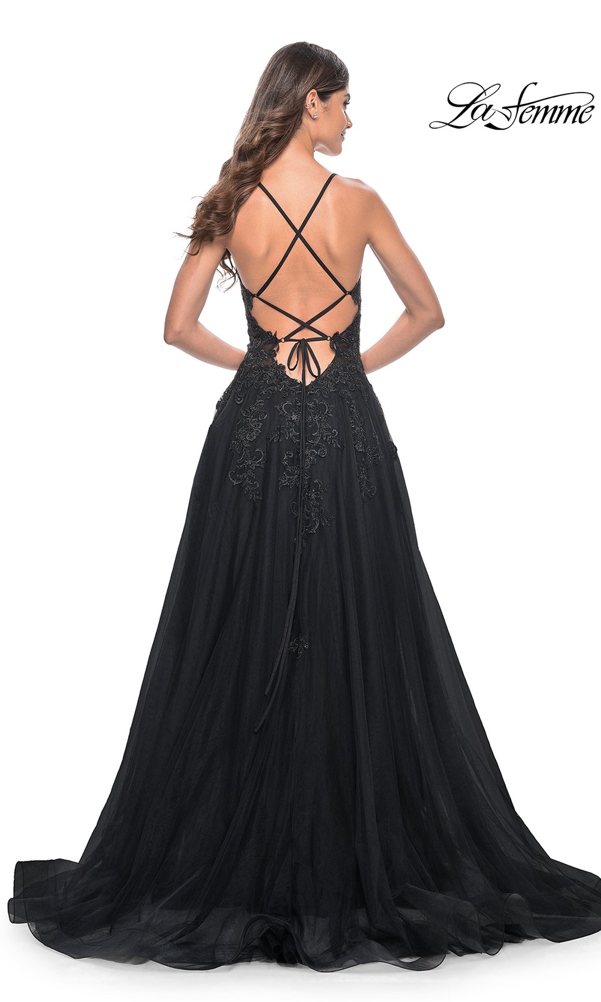 A woman wearing the La Femme Embroidered-Lace Long Prom Gown 32022, featuring a lace-up open back and embroidered details, stands facing away from the camera.