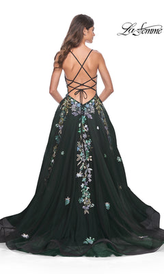 A woman models the La Femme Sequin Flower-Print Long Prom Dress 32023, featuring black fabric, sequin flower-print embroidery, an open back, and crisscross straps, against a white background.