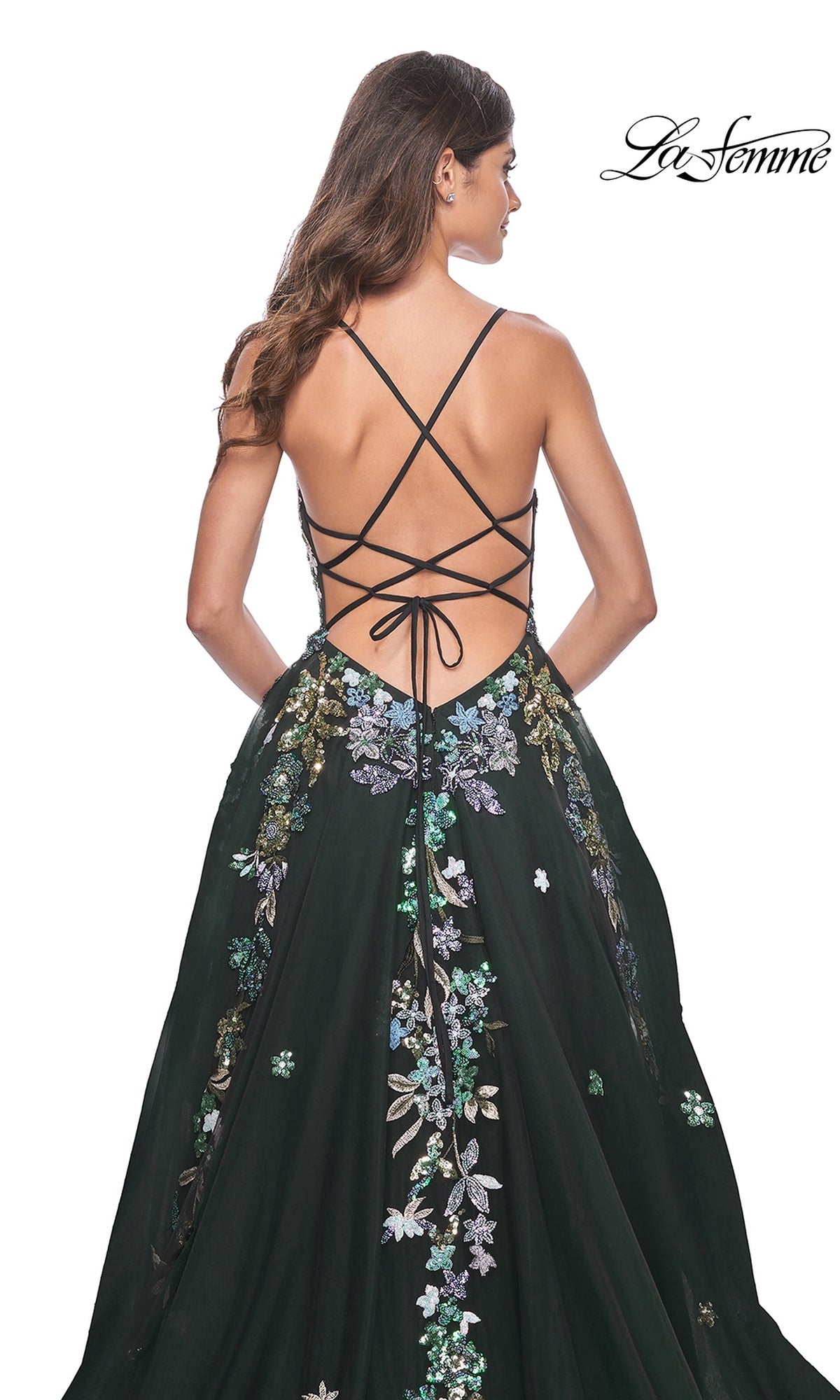 Woman in a black La Femme Sequin Flower-Print Long Prom Dress 32023 with crisscross back straps and sequin flower embroidery, standing with her back to the camera.
