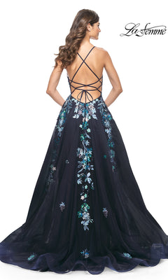 A woman with loose waves stands facing away in the La Femme Sequin Flower-Print Long Prom Dress 32023, featuring navy blue sequin floral embroidery and an open strappy back.