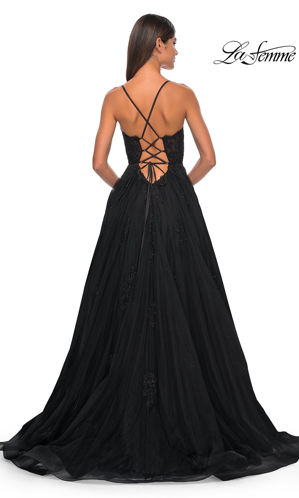 Woman modeling the La Femme Sheer-Corset Long A-Line Prom Dress 32028, a black open-back gown with lace-up crisscross detail and full flowing skirt, facing away from the camera—an elegant choice for any special occasion.