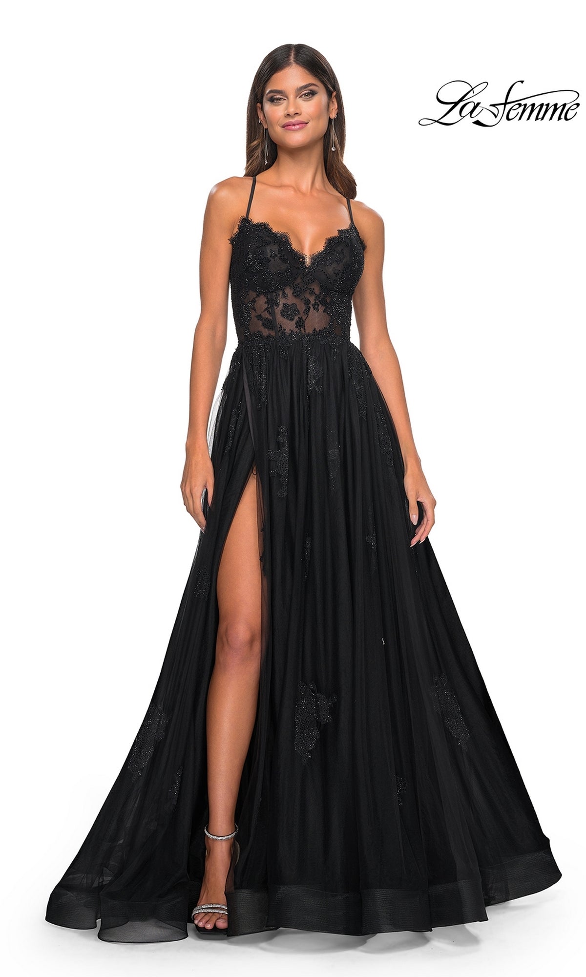 A woman models the La Femme Sheer-Corset Long A-Line Prom Dress 32028, featuring black embroidered lace, spaghetti straps, a high-slit skirt, and a lace bodice, all set against a plain white background for an effortlessly elegant look.