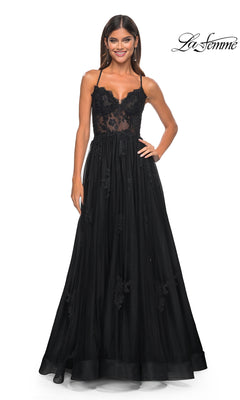 Woman wearing the La Femme Sheer-Corset Long A-Line Prom Dress 32028, a black floor-length embroidered lace gown with spaghetti straps, standing and smiling against a white background. "La Femme" logo in the top right corner.