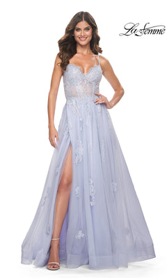 A woman wears the La Femme Sheer-Corset Long A-Line Prom Dress 32028 in light lavender with thin straps, a sheer bodice, floor-length A-line silhouette, leg slit, and embroidered lace. The La Femme logo appears in the top right corner.