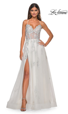 A woman wears the La Femme Sheer-Corset Long A-Line Prom Dress 32028, featuring embroidered lace, silver embellishments, a thigh-high slit, thin straps, and sheer detailing while standing against a plain background.