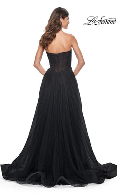 A woman is shown from the back wearing the La Femme Long Black Strapless Prom Ball Gown 32029, featuring a fitted bodice, flowing floor-length tulle skirt, and subtle sparkling details against a white background.