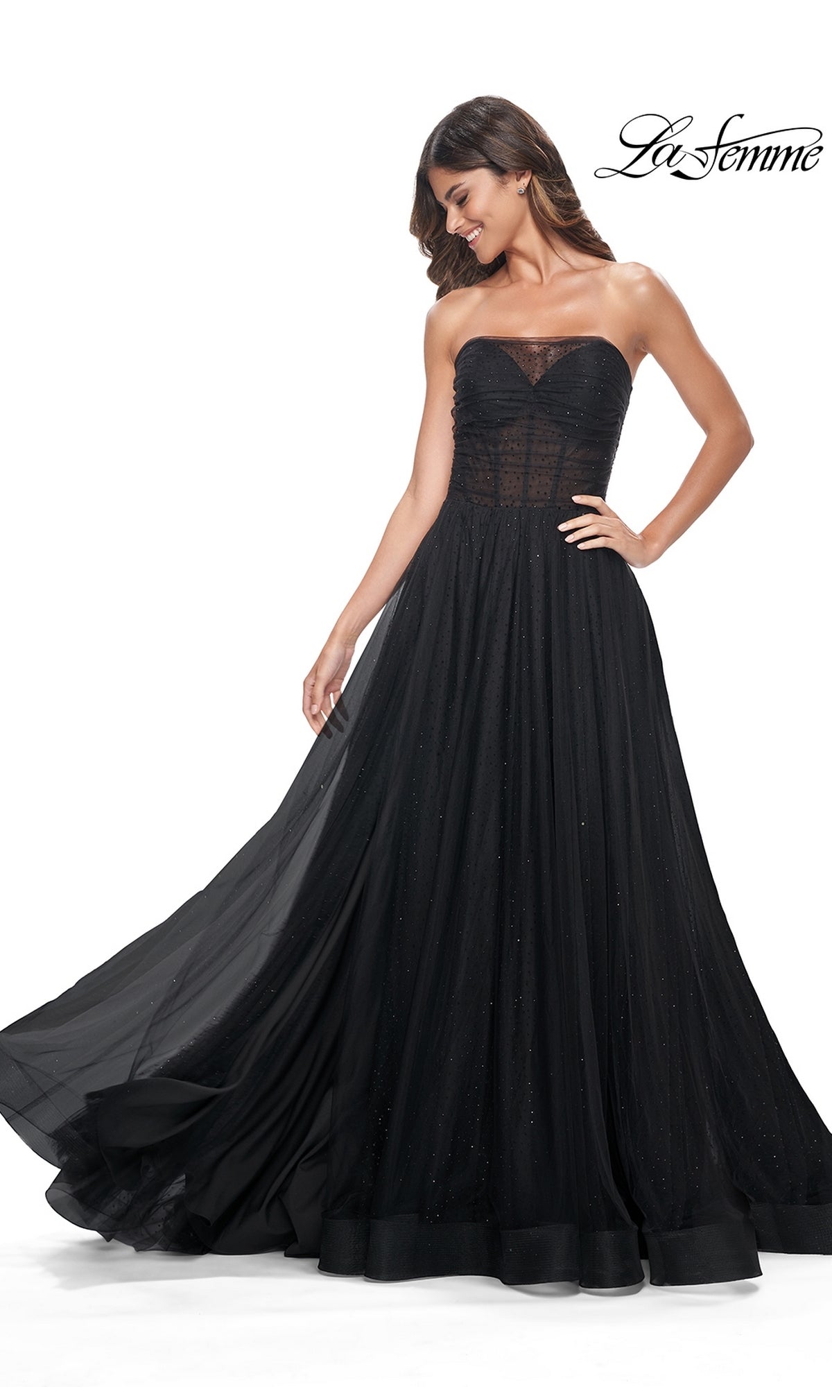 A woman poses against a white background in the La Femme Long Black Strapless Prom Ball Gown 32029, featuring a fitted bodice and flowing skirt. The 