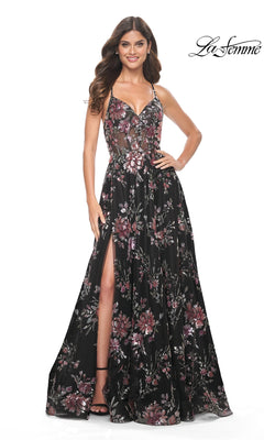 A woman stands smiling against a white background in the La Femme Floral-Sequin Long A-Line Prom Dress 32031, featuring black fabric, spaghetti straps, sequin floral detailing, a high slit, and a fitted bodice.