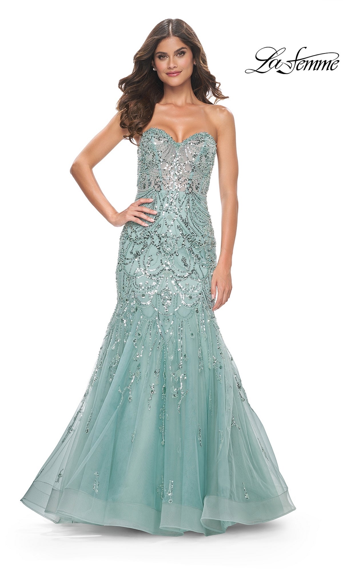 A woman poses with one hand on her hip in the La Femme Strapless Long Mermaid Prom Dress 32053, featuring a fitted light blue bodice, silver sequin embellishments, and a flowing tulle mermaid skirt for a glamorous look.