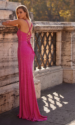 A woman in the La Femme Square-Neck Long Beaded Prom Dress 32058, featuring thin straps and a lace-up back, stands by a stone railing outdoors.