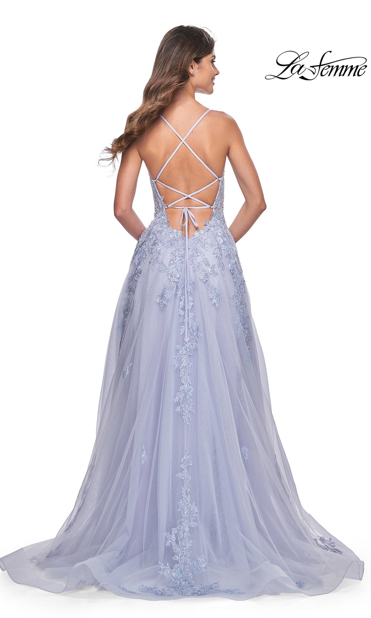 A woman faces away in the La Femme Embroidered-Lace Long Prom Dress 32062, featuring light purple floral embroidery, a crisscross strappy open back, and the 